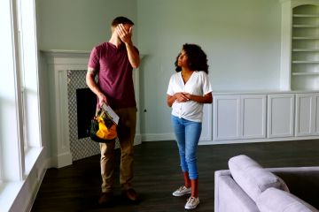 A homeowner discussing a renovation project with a licensed general contractor in Syracuse, NY, reviewing blueprints and project details before hiring.